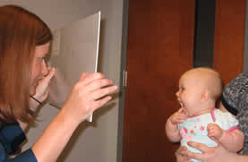 optometrist testing an infants visual acuity with a Teller card